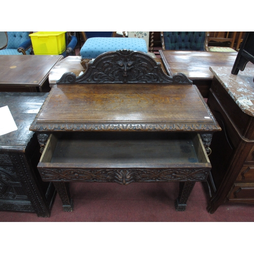 1573 - A XIX Century Carved Oak Side Table, with shaped back carved with a head, single drawer flanked by c... 