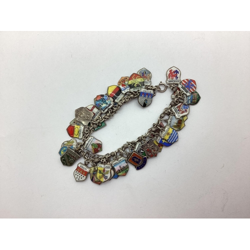 166 - A Vintage Enamel Shield Souvenir Charm Bracelet, suspending numerous assorted shield pendants.