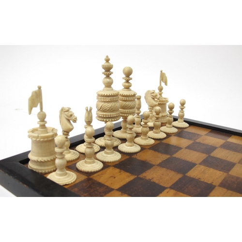 1282 - An Early XX Century Carved Bone Chess Set, with red stained and plain pieces, in box with board.