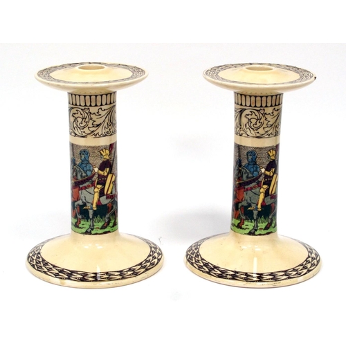 1121 - A Pair of Royal Doulton Pottery Candlesticks, the cylindrical columns decorated with knights on hors... 