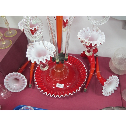 1033 - A Late XIX Century Red and White Glass Epergne, the shaped circular base with central trumpet vase s... 