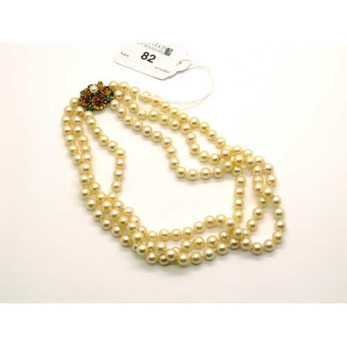 82 - A Three Strand Pearl Bead Necklace, the uniform pearls individually knotted to fancy push clasp of a... 