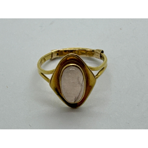 109 - An Oval Cabochon Set Ring, collet set between Modernist style surround, between bifurcated shoulders... 