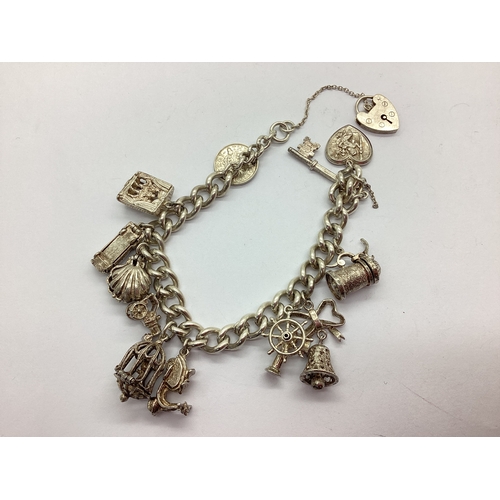 123 - A Chunky Curb Link Charm Bracelet, suspending assorted novelty charms, including articulated clam sh... 