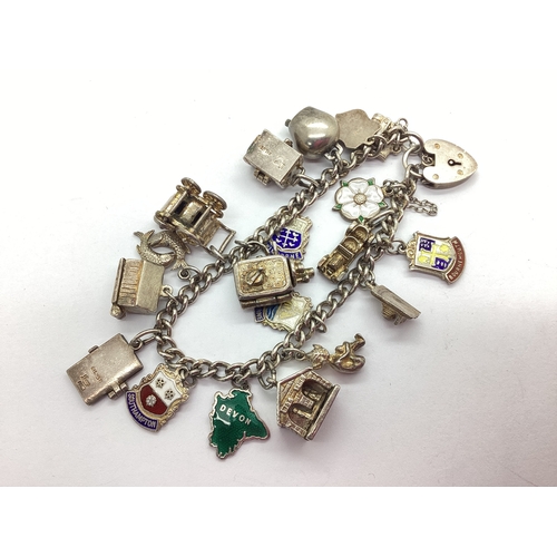 128 - A Chunky Curb Link Charm Bracelet, suspending assorted novelty charms, including enamelled souvenir,... 