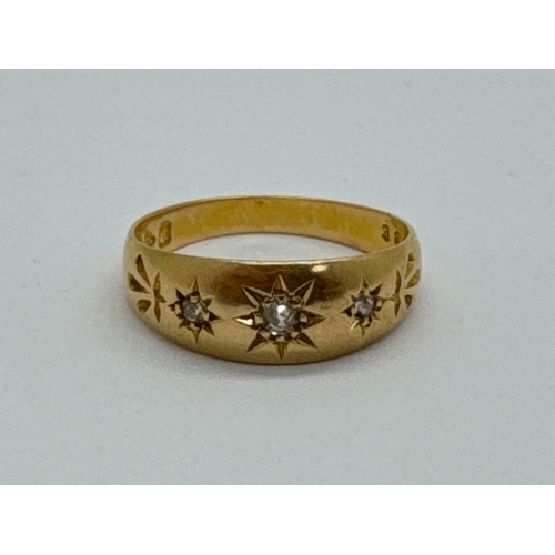 95 - An Antique 18ct Gold Three Stone Diamond Ring, the graduated brilliant cut stones within starburst s... 