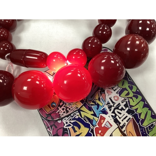 129 - A Cherry Coloured Beaded Necklace, the spherical beads of graduated size, to invisible barrel clasp,... 