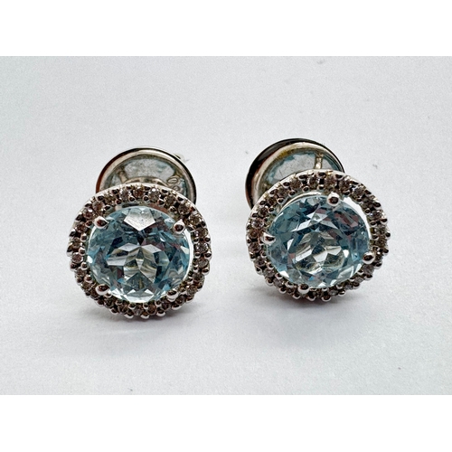 158 - A Pair of 18ct White Gold Diamond and Blue Topaz Earstuds, the circular stone four claw set between ... 