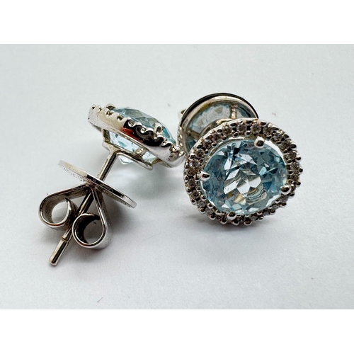 158 - A Pair of 18ct White Gold Diamond and Blue Topaz Earstuds, the circular stone four claw set between ... 