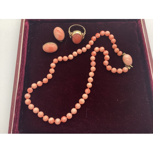 183 - A 9ct Gold Coral Dress Ring, oval collet rubover set, between scroll shoulders (finger size R); Toge... 