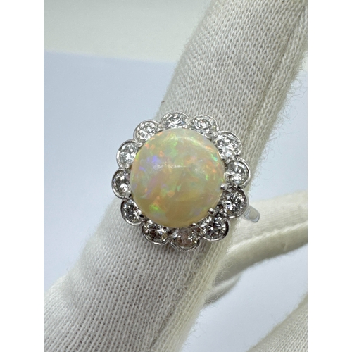 251 - A Large Opal and Diamond Cluster Ring, the central circular cabochon opal claw set within shaped bor... 