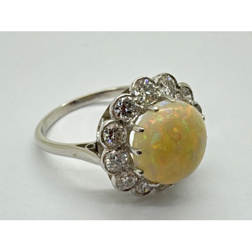 251 - A Large Opal and Diamond Cluster Ring, the central circular cabochon opal claw set within shaped bor... 