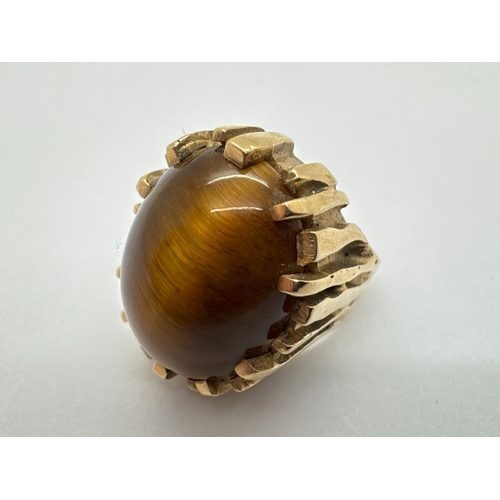 282 - A Modernist 9ct Gold Tiger's Eye Single Stone Ring, the oval cabochon stone within abstract claw set... 