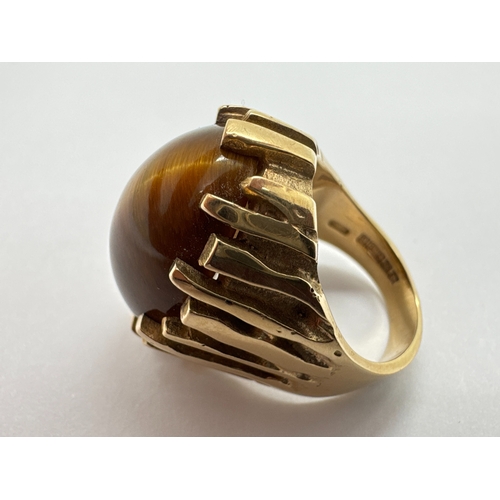 282 - A Modernist 9ct Gold Tiger's Eye Single Stone Ring, the oval cabochon stone within abstract claw set... 