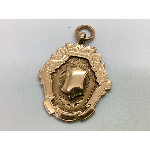 292 - A 9ct Gold Medallion Fob, in the form of a shield, with scrollwork decoration surround and vacant ce... 