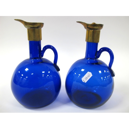 1009 - A Pair of 'Bristol' Blue Glass XIX Century Single Handled Ewers, with brass mounts and one stopper, ... 