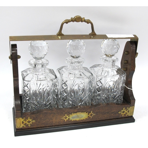 1521 - Oak Tantalus with brass mounts and a fall handle locking mechanism, housing three glass decanters, a... 