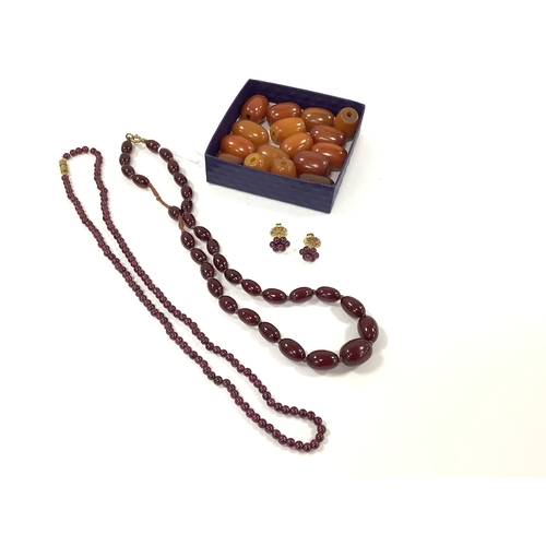 207 - A Vintage Cherry Amber Colour Single Strand Bead Necklace, together with a polished garnet bead neck... 