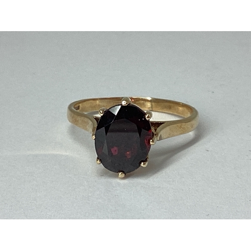 75 - A 9ct Gold Garnet Single Stone Dress Ring, oval claw set high between plain shoulders (finger size Q... 