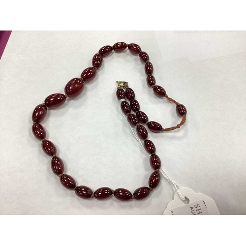 207 - A Vintage Cherry Amber Colour Single Strand Bead Necklace, together with a polished garnet bead neck... 
