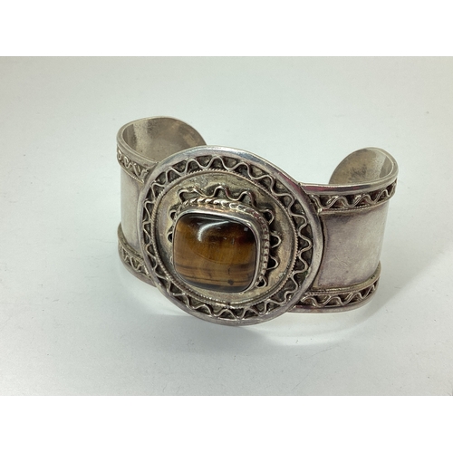 104 - A Tiger's Eye Inset Wide Cuff Bangle, cushion cabochon set to the centre, stamped 