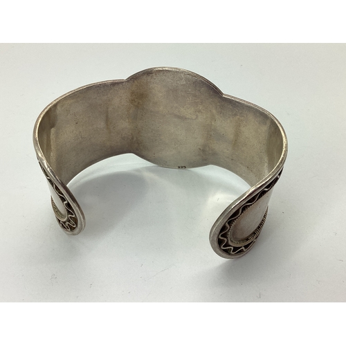 104 - A Tiger's Eye Inset Wide Cuff Bangle, cushion cabochon set to the centre, stamped 