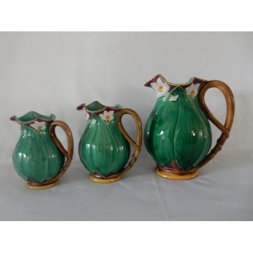 131 - A set of three graduated Minton majolica jugs decorated with pink flowers and green leaves, the larg... 