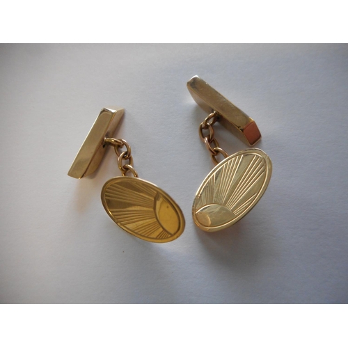 248 - A pair of 9ct. gold cufflinks with sunray decoration to the oval fronts