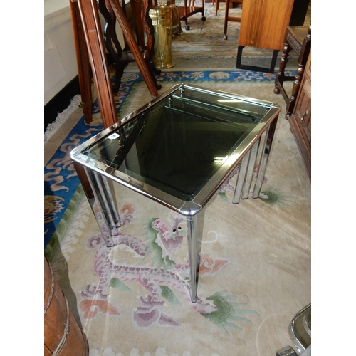 35 - A modern chrome and smoked glass two tier drinks trolley and a nest of three chrome occasional table... 