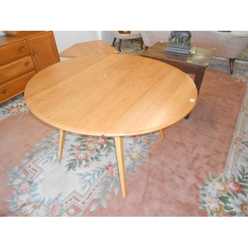 28 - An Ercol light elm dining table fitted two rounded drop flaps, on splayed legs - 45in. wide