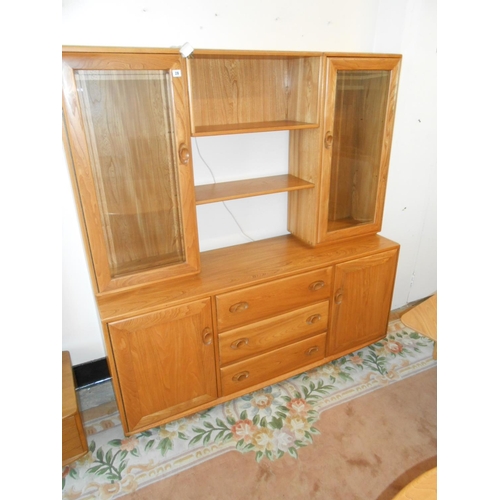 29 - An Ercol elm display cabinet, the upper part fitted centre shelves flanked to each side by glass fro... 