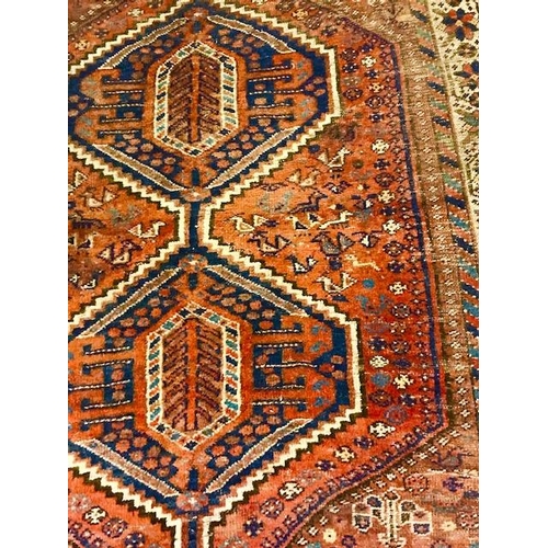 3 - An Eastern rug, red field with stylised blue and orange centre, multi bordered, fringed