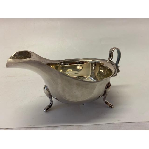 190 - A silver sauce boat with serpentine edge, on three feet - Sheffield 1966, makers marks for Viners