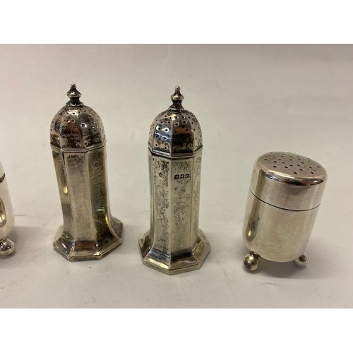 205 - A pair of panelled silver pepperettes - London 1917  and a pair of plain silver cylindrical pepperet... 