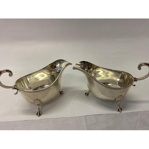 228 - A pair of Asprey silver sauce boats with leaf scroll handles,  gadroon handles, on three leaf clad p... 