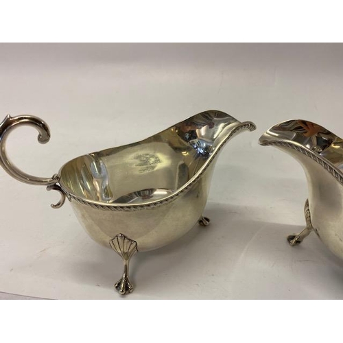 228 - A pair of Asprey silver sauce boats with leaf scroll handles,  gadroon handles, on three leaf clad p... 