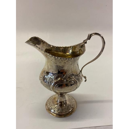 237 - A Georgian silver cream jug with punched rim, beaded handle, flower and leaf scroll decoration, on c... 