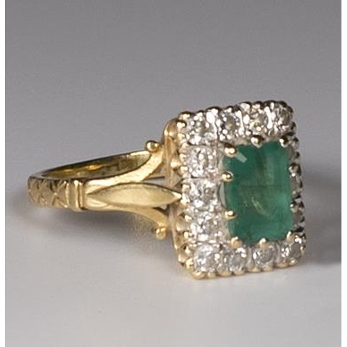 289 - A lady's ring set rectangular emerald surrounded by diamonds, on an 18ct. gold shank with split shou... 