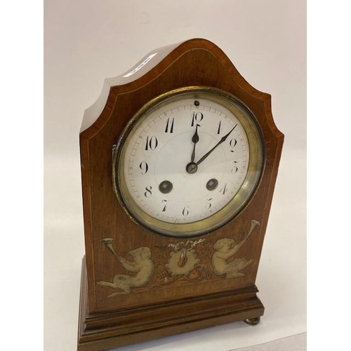 296 - An Edwardian mantel clock, white enamel dial, in a walnut case with shaped top and inlaid putti to t... 