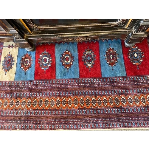 4 - An Eastern style rug with red and blue alternate panels to the centre, multi bordered - 75in. x 50in... 