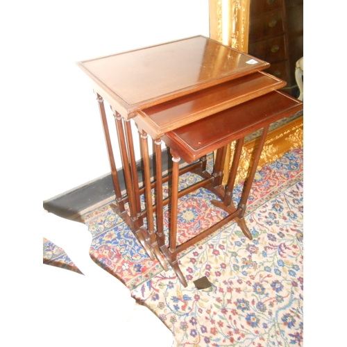 105 - A nest of three mahogany occasional tables on twin spindle supports, the largest - 18in. wide
