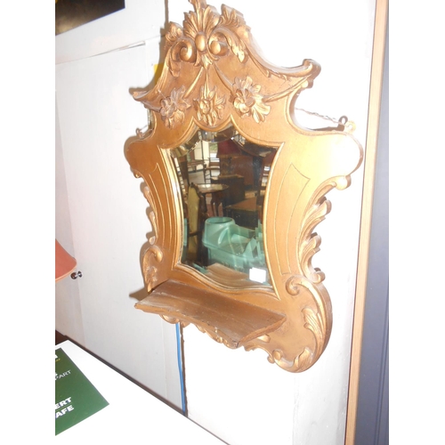 99 - A pair of wall mirrors in gilt frames with flower decoration, each fitted shelf