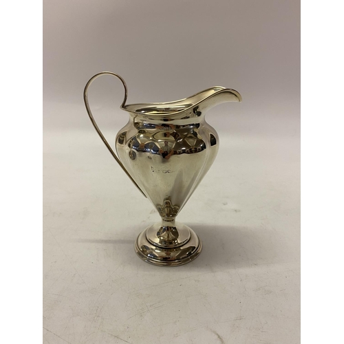 169 - A silver pedestal cream jug of lobed form, scroll handle, on circular foot