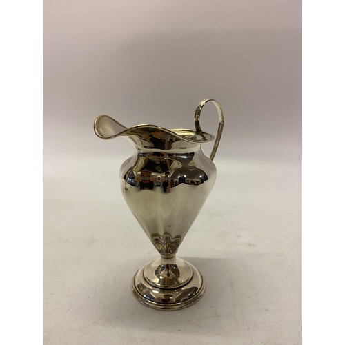 169 - A silver pedestal cream jug of lobed form, scroll handle, on circular foot