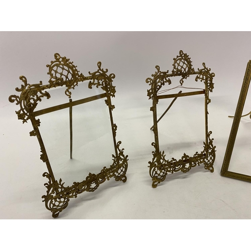 233 - A pair of brass photograph frames with scroll decoration, easel backs and one other with ribbon tie ... 