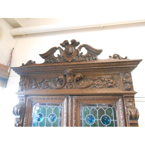 61 - A Victorian oak cabinet, the upper part with leaf scroll carved frieze above two leaded glass doors ... 