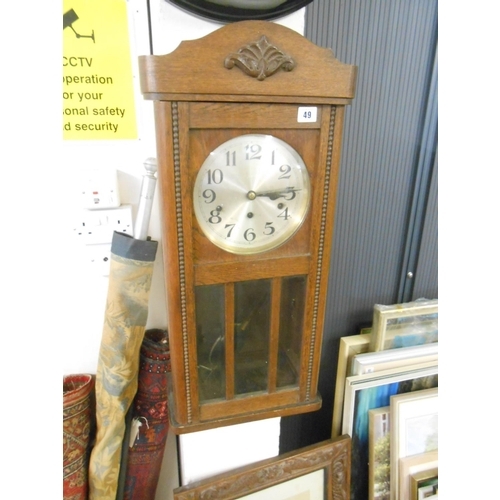 49 - A 1930's wall clock with circular silvered dial, in an oak case with glass panelled door