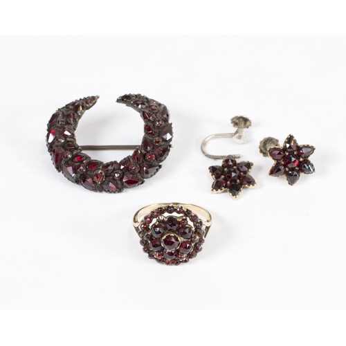 176 - A lady's cluster ring set garnets, on a gold coloured metal shank, a garnet set crescent form brooch... 