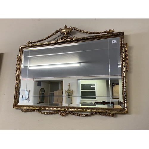 62 - A rectangular bevelled wall mirror in a gilt frame with urn and harebell swag pediment - 30in. x 38i... 