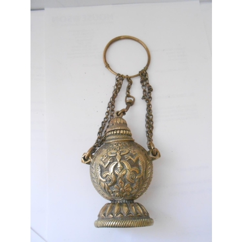 397 - A brass inkwell of urn form with repousse decoration of flowers, on hanging chain - 4 1/2in. high